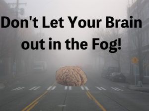Picture of a foggy day in a city with a brain on a street that's in the fog.